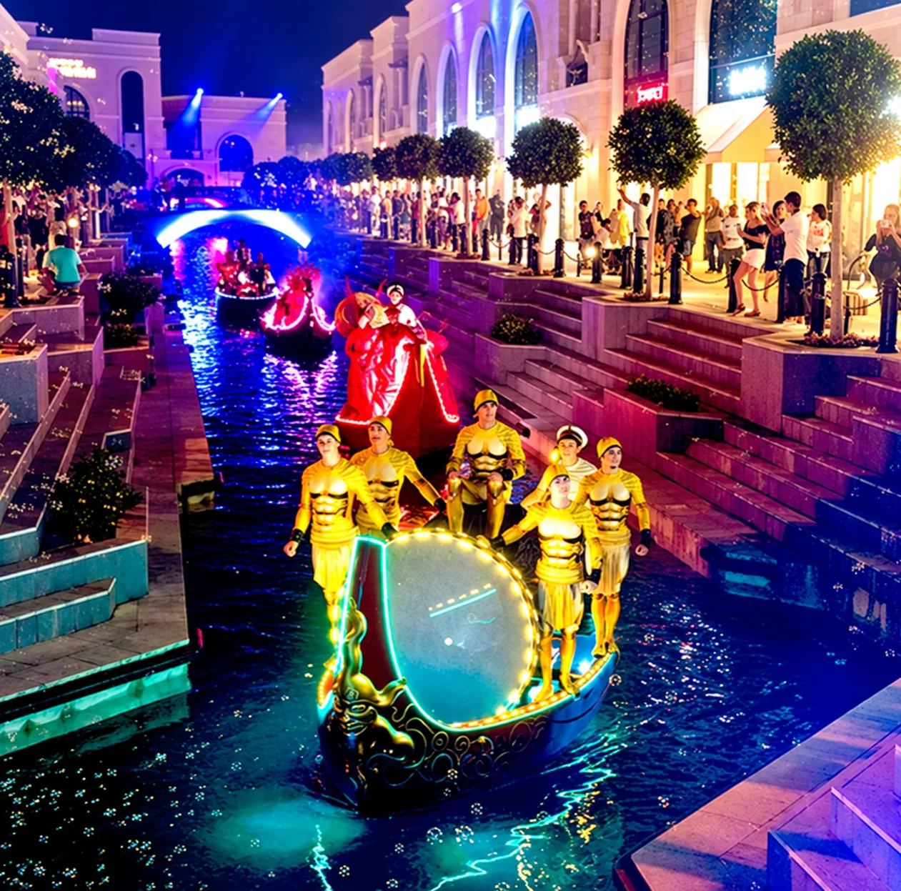 Illuminated show boats moving along the canal during an evening performance